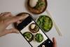 Jemand fotografiert mit dem Handy Teller mit Gemüse, Ansicht von oben