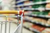 Generic supermarket trolly closeup with grocery aisle in background blurred