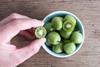Hand greift in Schale mit Kiwibeeren