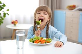 Young girl eating vegetables