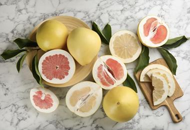 Cut and whole pomelos on marble surface