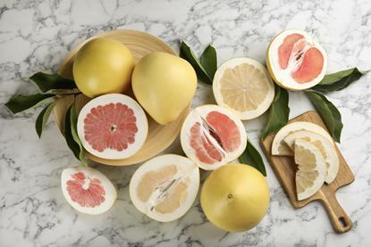 Cut and whole pomelos on marble surface