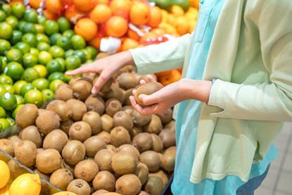 Frau beim Einkauf von Kiwis am PoS