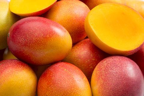 Whole and halved mangoes close up Adobe Stock