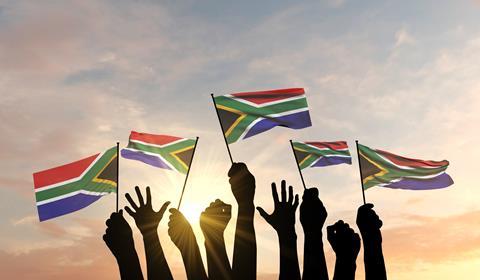 Hands waving South African flags Adobe