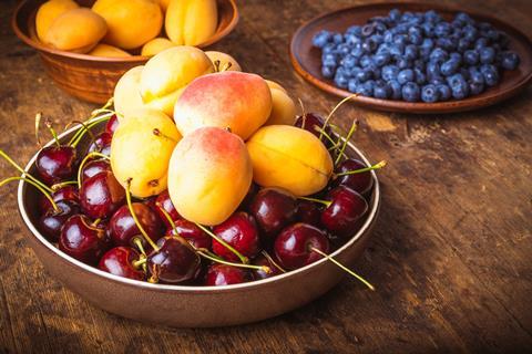 Apricots cherries blueberries on table Adobe