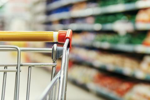 Generic supermarket trolly closeup with grocery aisle in background blurred