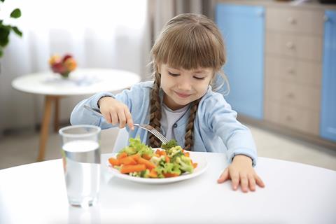 Small girl eating vegetables on plate